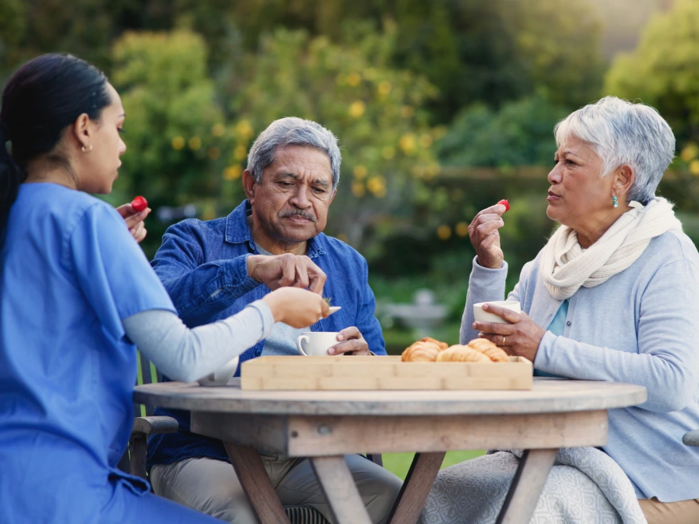 Two people enjoy a meal outdoors during companion care service with Thrive On Care.