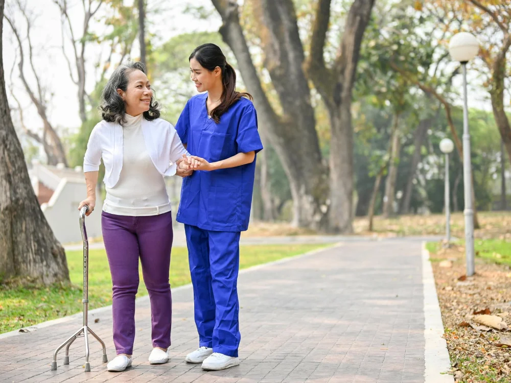 Two women walk together receiving mobility support from Thrive On Care caregivers.