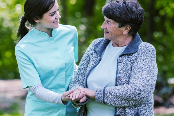 Thrive On Care supports mobility assistance for two women walking in a park.