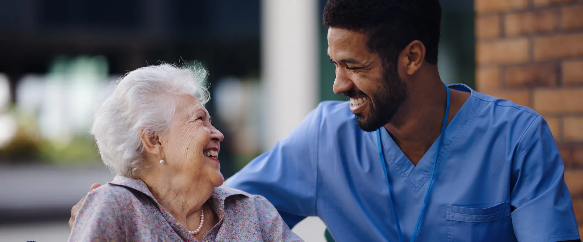 A woman chats with a man in a blue shirt while receiving companion care from Thrive On Care.